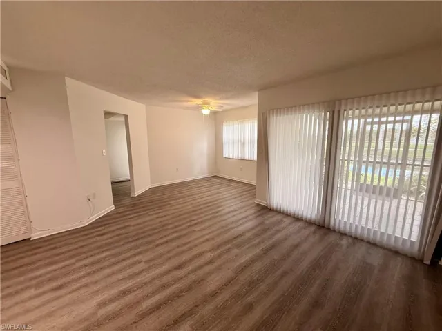 Unfurnished room with a textured ceiling, dark wood-style flooring, and ceiling fan