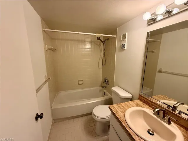 Bathroom featuring vanity, washtub / shower combination, and light tile patterned flooring