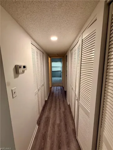Corridor with a textured ceiling and dark wood-style flooring