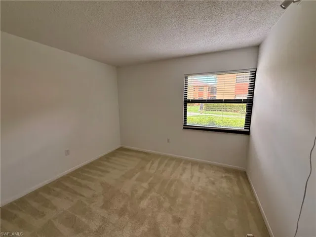Empty room featuring a textured ceiling and light carpet