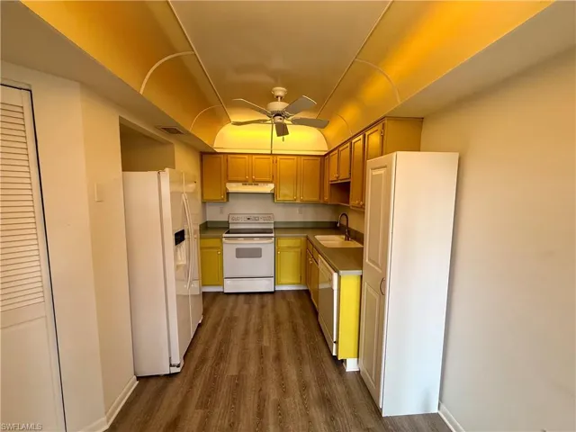 Kitchen featuring white appliances, a ceiling fan, and dark wood-style flooring