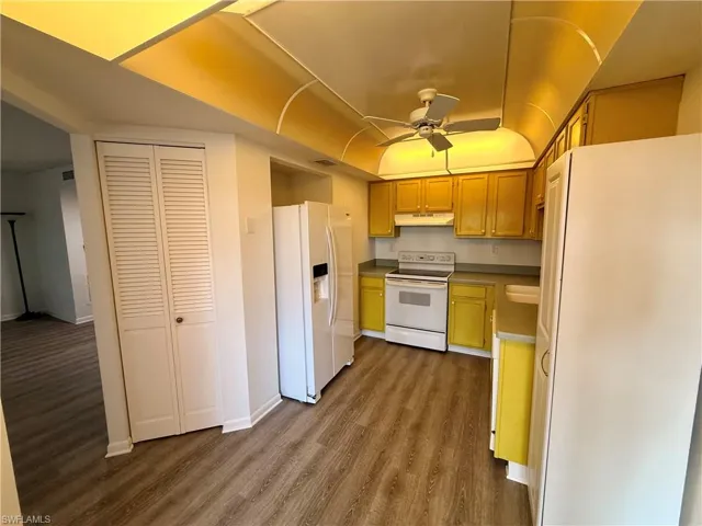 Kitchen with white appliances, a ceiling fan, and dark wood-style flooring