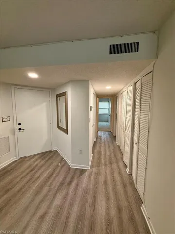 Hall with a textured ceiling and dark wood-style floors