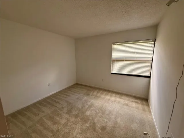Empty room featuring a textured ceiling and light colored carpet