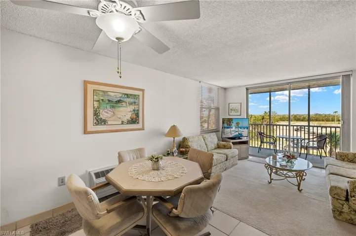 Tiled dining space featuring a textured ceiling, an AC wall unit, ceiling fan, and floor to ceiling windows