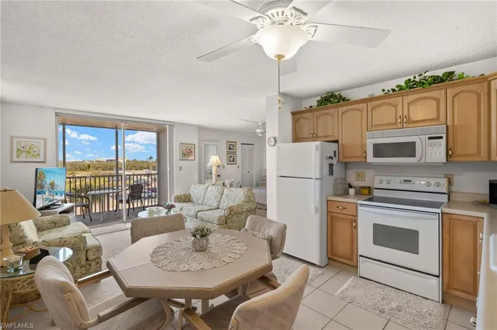 Kitchen with open floor plan, light countertops, light tile patterned flooring, white appliances, and a ceiling fan