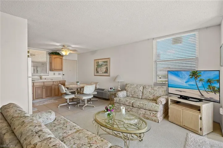 Living room featuring light tile patterned floors, a ceiling fan, and a textured ceiling