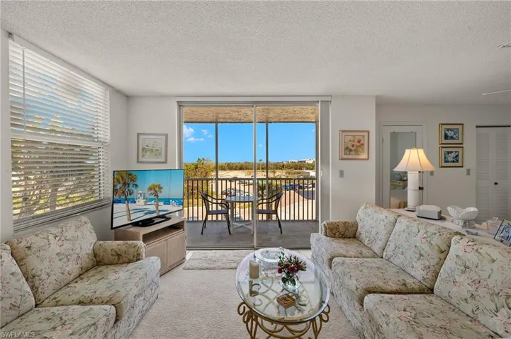 Living room featuring expansive windows, carpet floors, and a textured ceiling