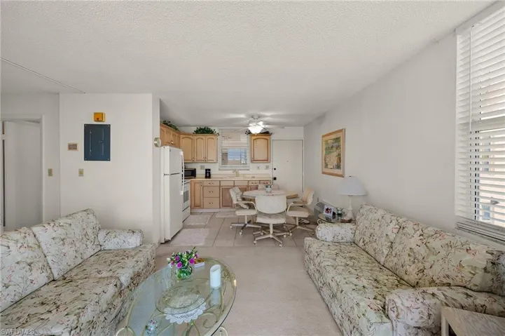 Living room with a ceiling fan, electric panel, a healthy amount of sunlight, and a textured ceiling