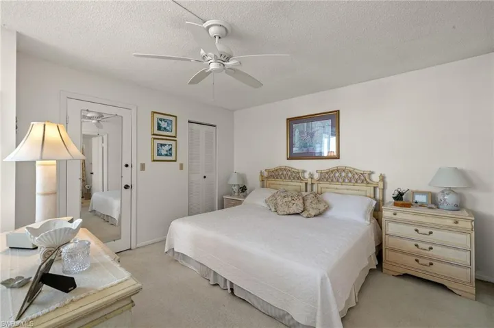 Bedroom featuring a textured ceiling, ceiling fan, a closet, and light carpet