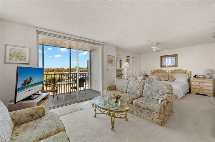 Living area with floor to ceiling windows, a ceiling fan, carpet floors, and a textured ceiling