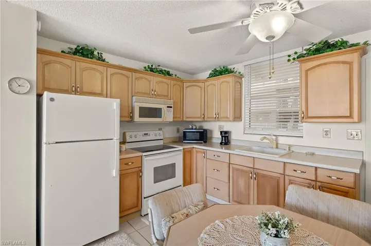 Kitchen featuring light brown cabinets, white appliances, light countertops, and a sink