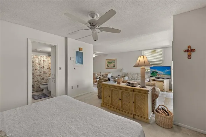 Bedroom with light colored carpet, ceiling fan, and a textured ceiling