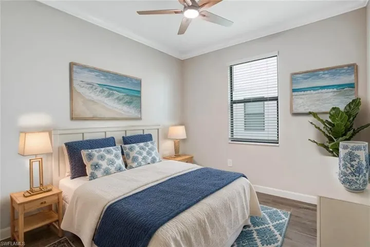 Bedroom featuring baseboards, wood finished floors, crown molding, and a ceiling fan