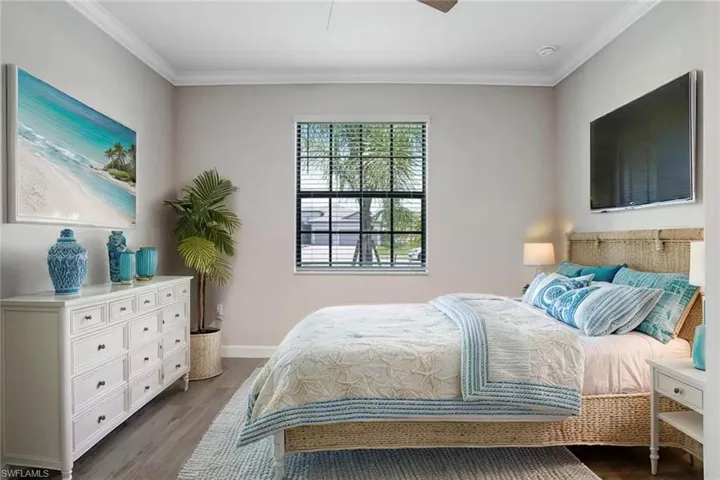 Bedroom featuring dark wood finished floors, crown molding, baseboards, and ceiling fan