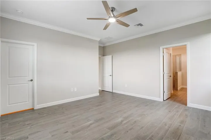 Unfurnished bedroom with ornamental molding, light wood-style floors, baseboards, and a ceiling fan