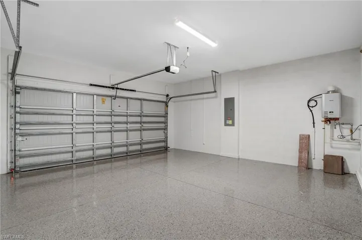 Garage featuring tankless water heater, electric panel, and a garage door opener