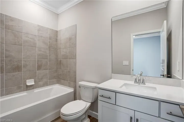Full bathroom featuring crown molding, toilet, vanity, and bathtub / shower combination