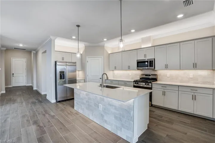 Kitchen featuring stainless steel appliances, a sink, ornamental molding, backsplash, and light countertops