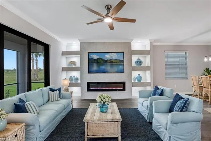 Living area with ceiling fan, crown molding, wood finished floors, and a fireplace