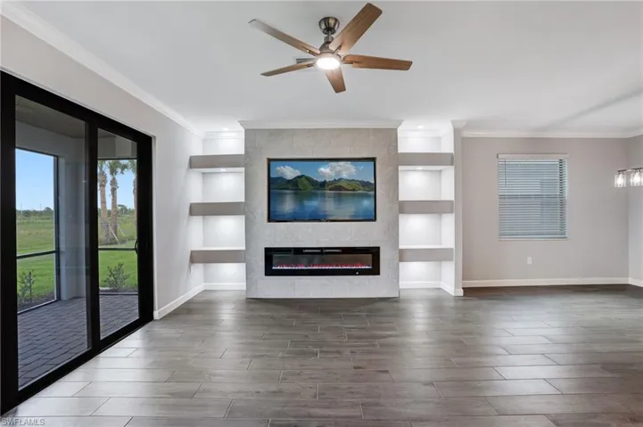 Unfurnished living room with ornamental molding, baseboards, wood finished floors, and ceiling fan