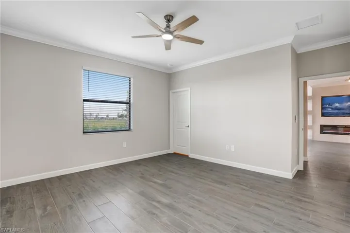 Spare room featuring ceiling fan, ornamental molding, wood finished floors, and baseboards