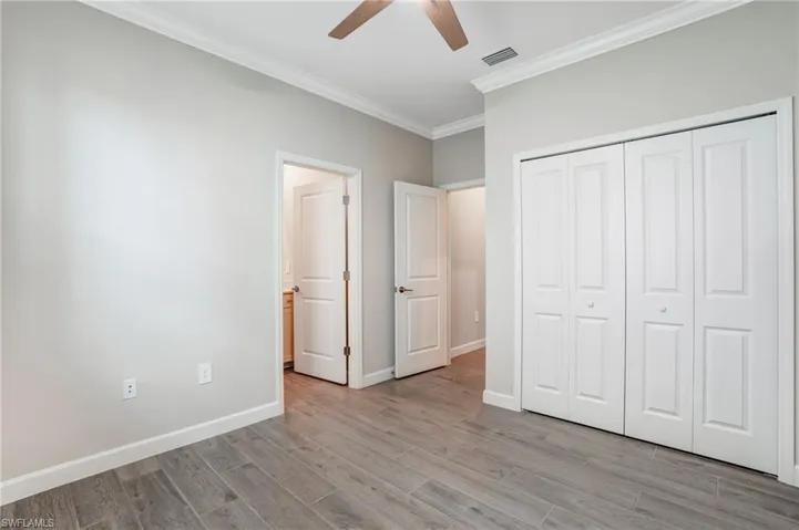 Unfurnished bedroom featuring ornamental molding, light wood-type flooring, a closet, baseboards, and ceiling fan