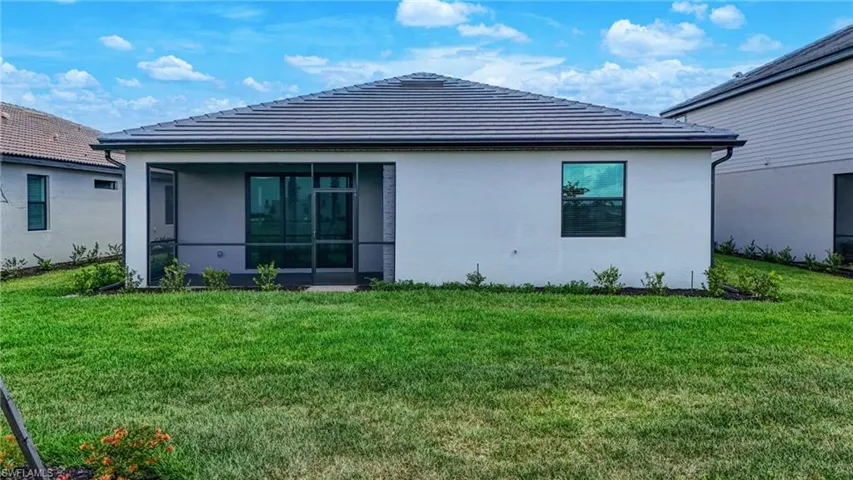 Back of property with a lawn, a sunroom, and stucco siding