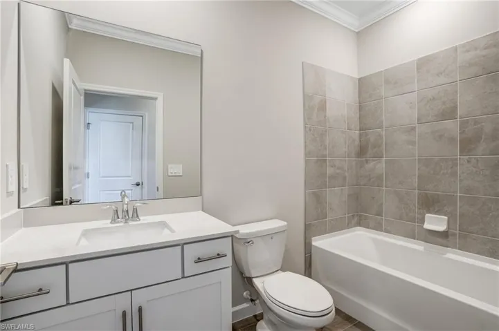 Full bathroom featuring crown molding, vanity, toilet, and shower / washtub combination
