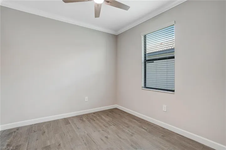 Empty room with baseboards, ceiling fan, crown molding, and wood finished floors