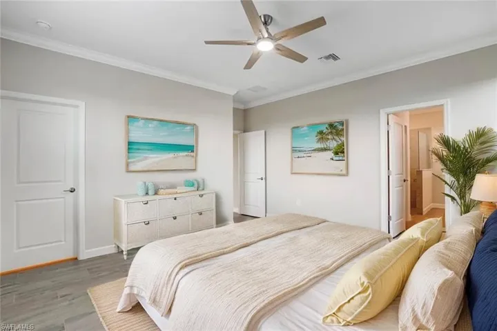 Bedroom featuring wood finished floors, crown molding, baseboards, and ceiling fan