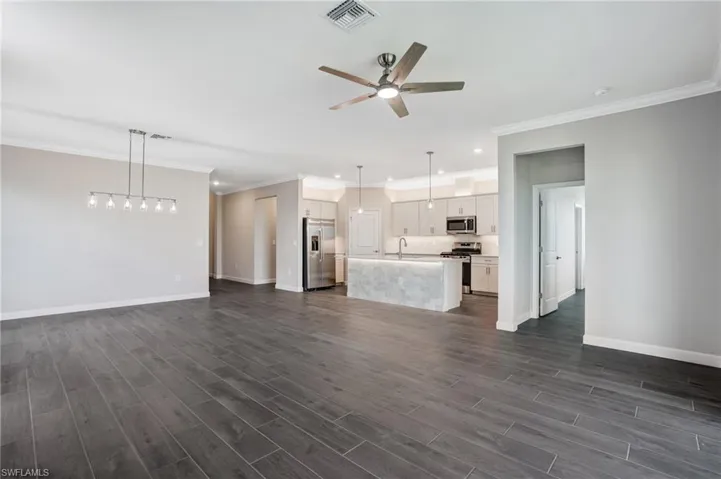 Unfurnished living room featuring a sink, ceiling fan, baseboards, ornamental molding, and recessed lighting