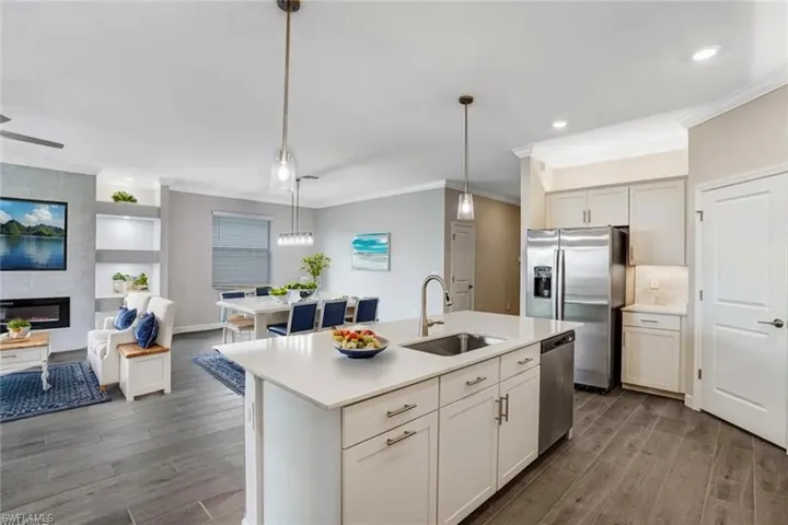 Kitchen featuring a sink, appliances with stainless steel finishes, crown molding, dark wood finished floors, and light countertops
