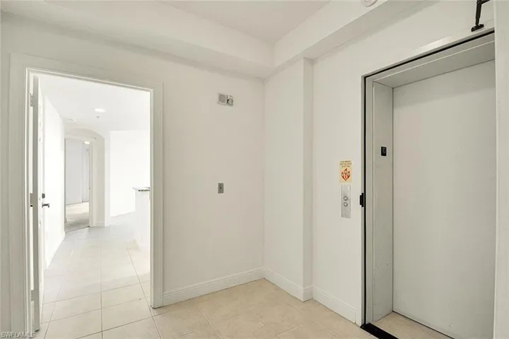 Hall featuring elevator, light tile patterned floors, and arched walkways