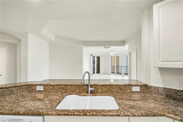 Kitchen with white cabinets, dark stone counters, open floor plan, and ceiling fan
