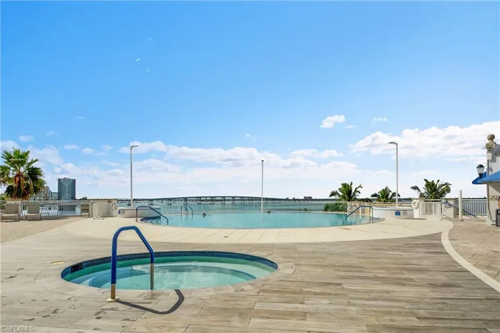 Community pool with a hot tub, a patio area, and a water view