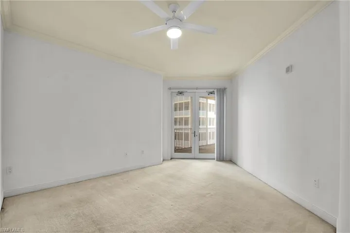 Carpeted empty room featuring ornamental molding, a ceiling fan, and french doors