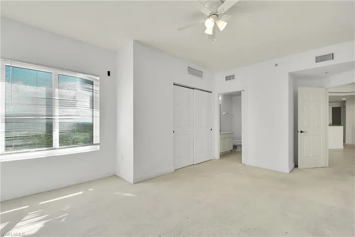 Unfurnished bedroom with light carpet, a closet, ceiling fan, and ensuite bath