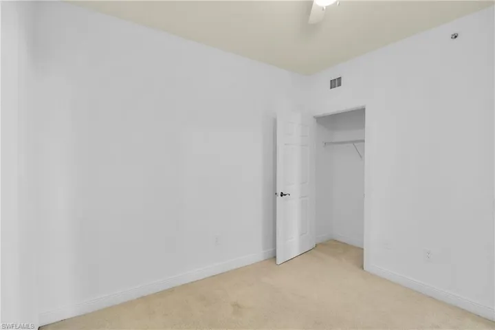 Unfurnished bedroom with light carpet, a closet, and a ceiling fan