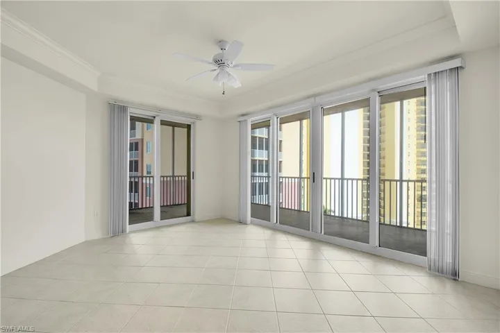 Spare room featuring crown molding, light tile patterned flooring, ceiling fan, and a raised ceiling