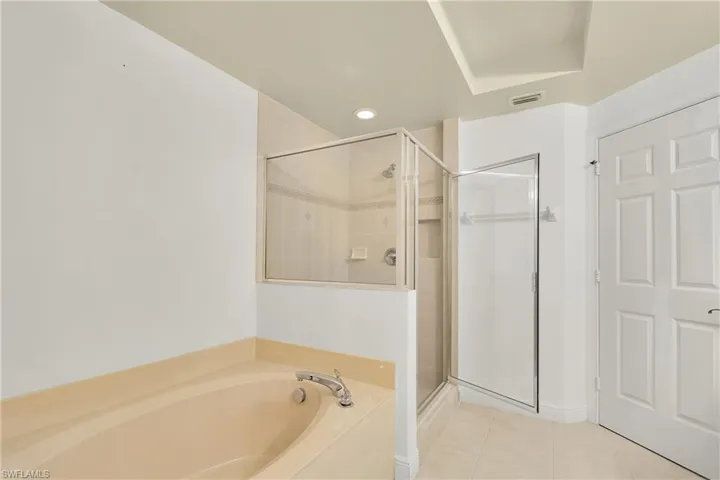 Bathroom with light tile patterned flooring, a garden tub, a shower stall, and recessed lighting
