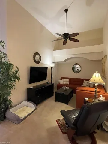 Den with light carpet, high vaulted ceiling, and ceiling fan