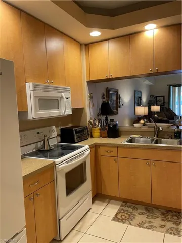 Kitchen with fridge, sink, light tile patterned floors, and white range oven