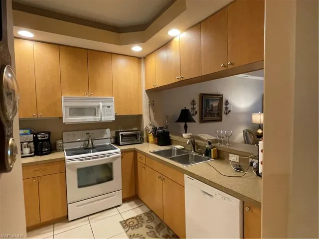 Kitchen featuring stove, dishwasher, light tile patterned floors, and sink