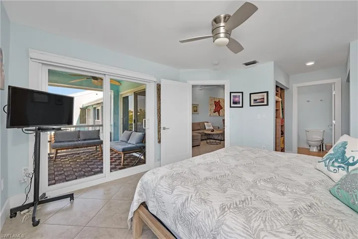 Bedroom featuring access to exterior, ceiling fan, light tile patterned floors, and ensuite bathroom