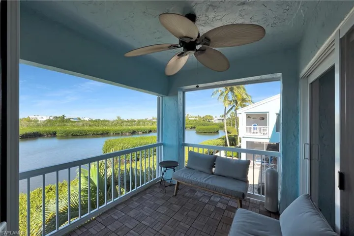 Sunroom with ceiling fan and a water view