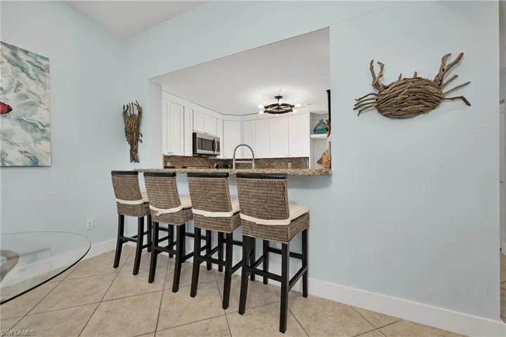 Kitchen featuring white cabinetry, backsplash, kitchen peninsula, a breakfast bar area, and light tile patterned flooring