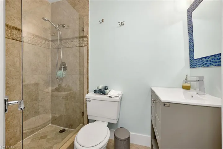 Bathroom featuring vanity, toilet, and tiled shower