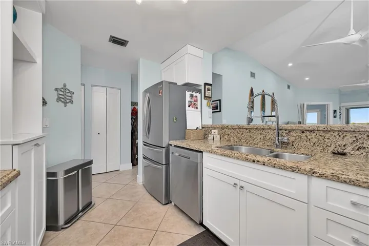 Kitchen featuring dishwasher, white cabinets, sink, ceiling fan, and light stone counters