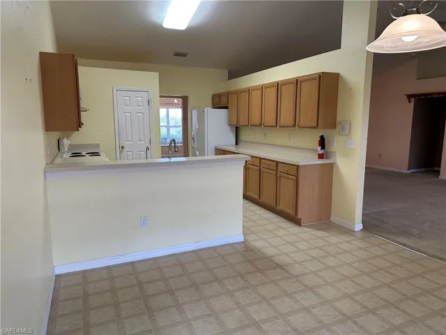 Kitchen featuring light countertops, brown cabinets, white fridge with ice dispenser, and light floors